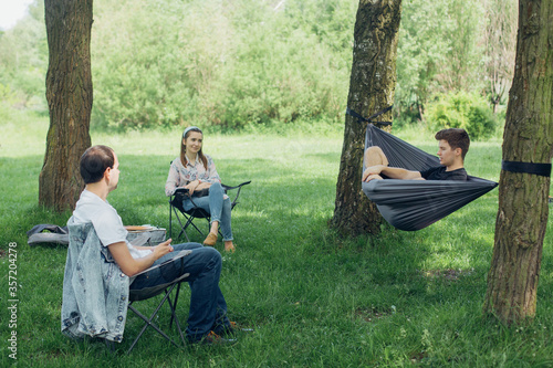 Obraz na płótnie Small group of people enjoying conversation at picnic in accordance with social distancing in summer park