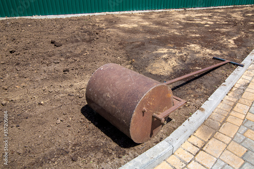 Wallpaper Mural garden roller for compaction of the soil an iron shaft lies on the rolled ground on a sunny day, closeup of a landscape design process nobody. Torontodigital.ca