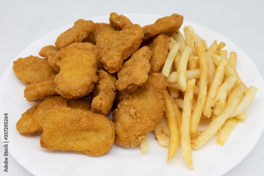 Chicken Nuggets and French Fries on a White Plate with a White Background Chicken Nuggets and French Fries on a White Plate with a White Background