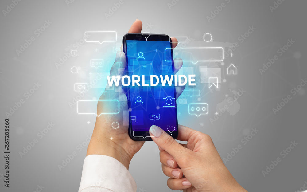 Female hand typing on smartphone with WORLDWIDE inscription, social media concept Female hand typing on smartphone with WORLDWIDE inscription, social media concept