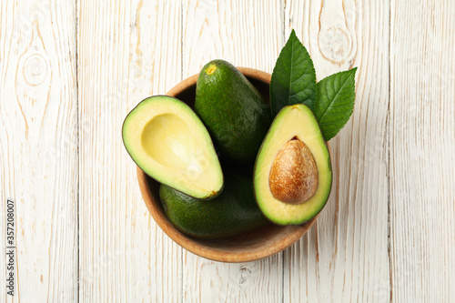 Bowl with fresh avocado on wooden background, top view