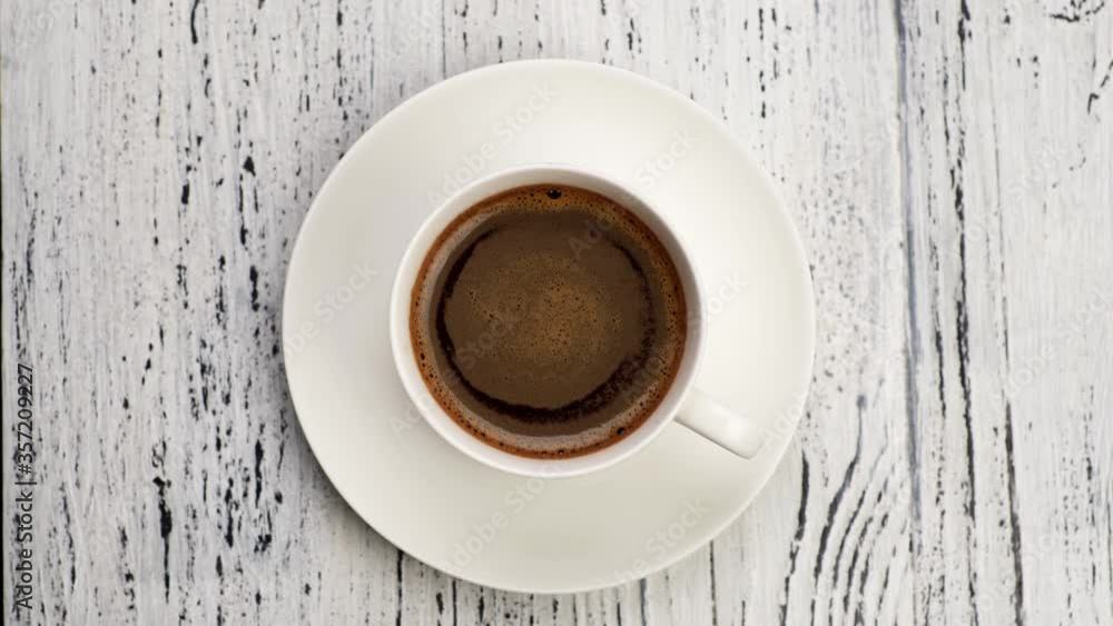 Top down shot of coffee foam swirls in white cup with coffee. Old wooden background, 4K Top down shot of coffee foam swirls in white cup with coffee. Old wooden background, 4K