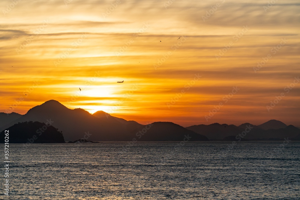 Landscape of the sea with the silhouettes of hills during the sunset in Brazil on the background
