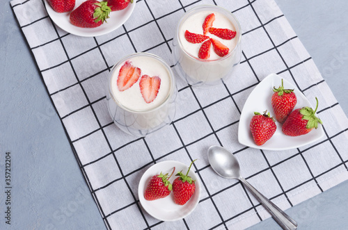 Strawberry dessert in a glass jar with strawberries on a gray table