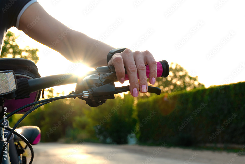 .Hand of a girl on the wheel of a bicycle in the rays of the setting sun. Girl rides a bicycle in the evening