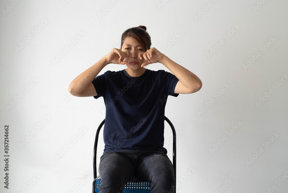 Unhappy woman sitting against on the wall,raise finger touch her face and crying,upset and stress feeling Unhappy woman sitting against on the wall,raise finger touch her face and crying,upset and stress feeling
