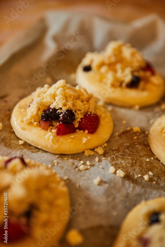 Obraz na płótnie homemade buns with fruit and crumble on white baking paper ready for baking in the oven. w salonie