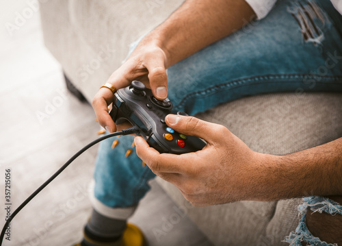 Beauty male hands using joystick. Gamer uses wired gamepad playing computer games. Close up shot. Home entertainment concept. Toned image.