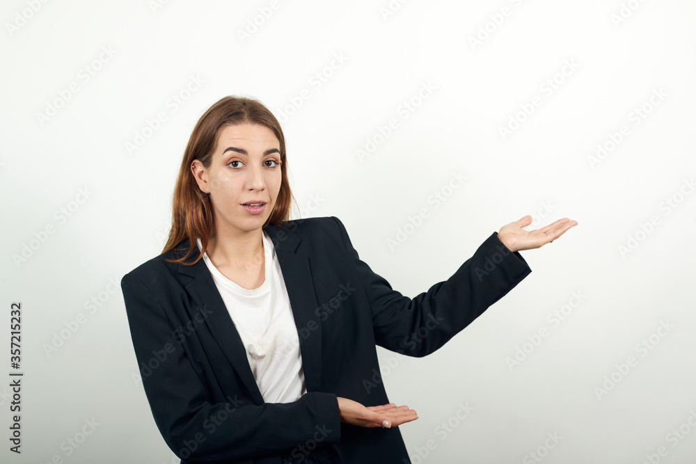 Shows direction of hands, demonstrates your product, represents an imaginary output, blank targeting, folded arm bent arrow. young attractive woman with brown hair in a light t-shirt, black jacket Shows direction of hands, demonstrates your product, represents an imaginary output, blank targeting, folded arm bent arrow. young attractive woman with brown hair in a light t-shirt, black jacket