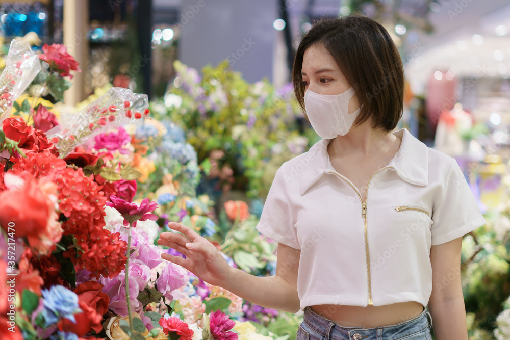 Woman wearing face mask chooses a flower at shop, during coronavirus pandemic.