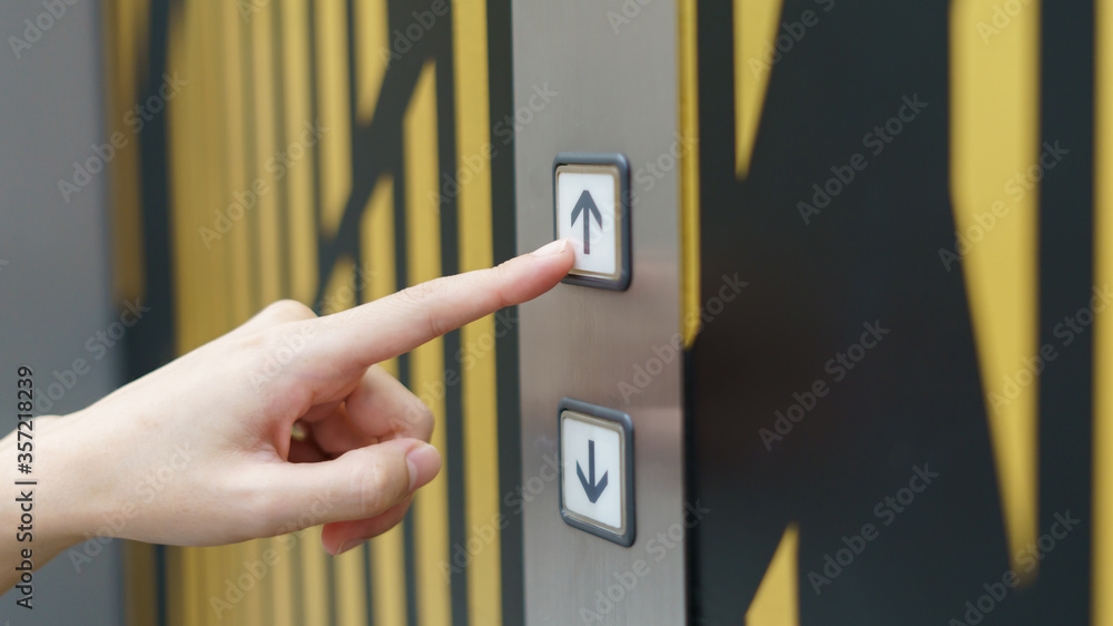 Naklejka premium Woman finger pressing a up button of elevator button inside the building.