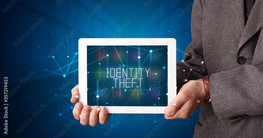 Young business person working on tablet and shows the digital sign: IDENTITY THEFT Young business person working on tablet and shows the digital sign: IDENTITY THEFT