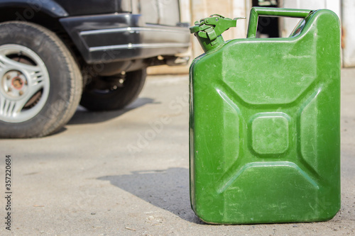 Green jerry can close-up on blurred background of black car