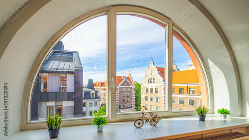 Arch semicircle window. View of old town of Riga, Latvia. Flowers and decorative bicycle on the sill.