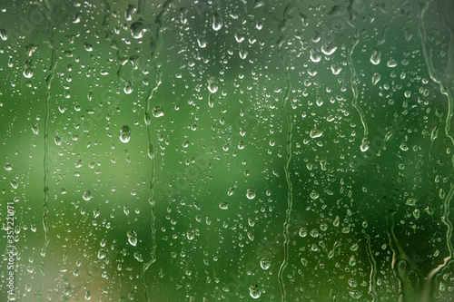 Drops of water on glass on a green background in blurred focus 