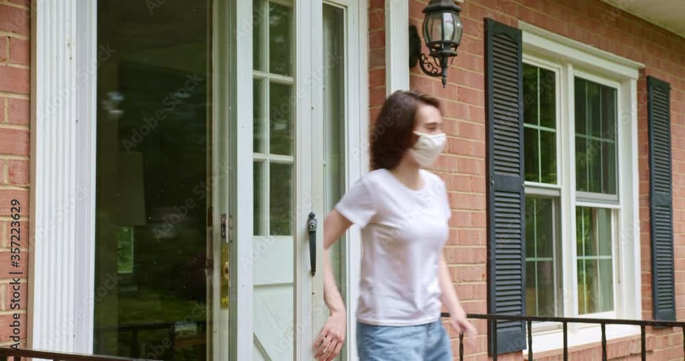 Young attractive female leaves house wearing face mask to protect against Covid-19 and to slow the spread of the virus. Young attractive female leaves house wearing face mask to protect against Covid-19 and to slow the spread of the virus.
