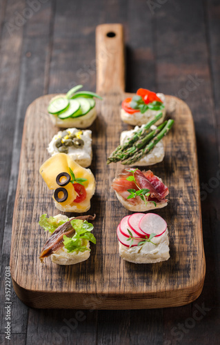 Set of different mini canapes served on a wooden board. Catering finger food.