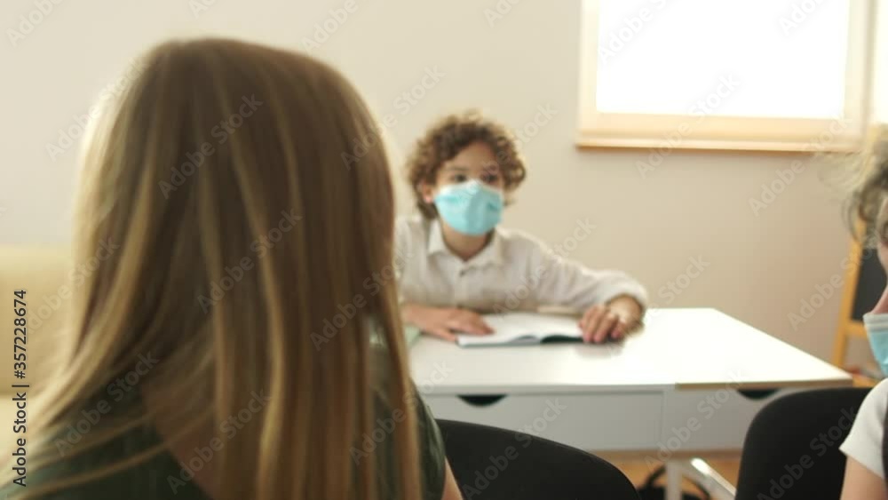 Children in protective masks at school in a lesson. Post-quarantine school, new normality, new rules, social distance Children in protective masks at school in a lesson. Post-quarantine school, new normality, new rules, social distance