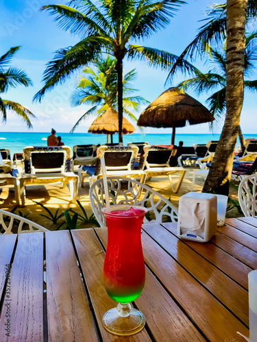 Cocktail drink glass in close-up on a Caribbean beach in Cancun, Mexico.