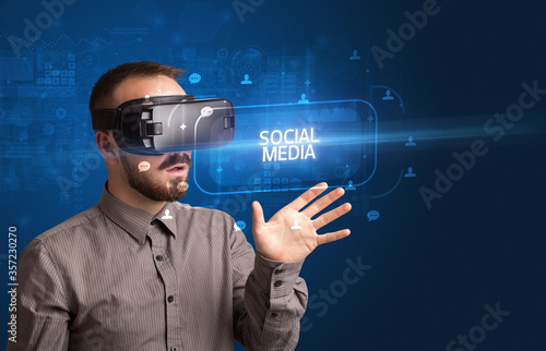 Businessman looking through Virtual Reality glasses with SOCIAL MEDIA inscription, social networking concept