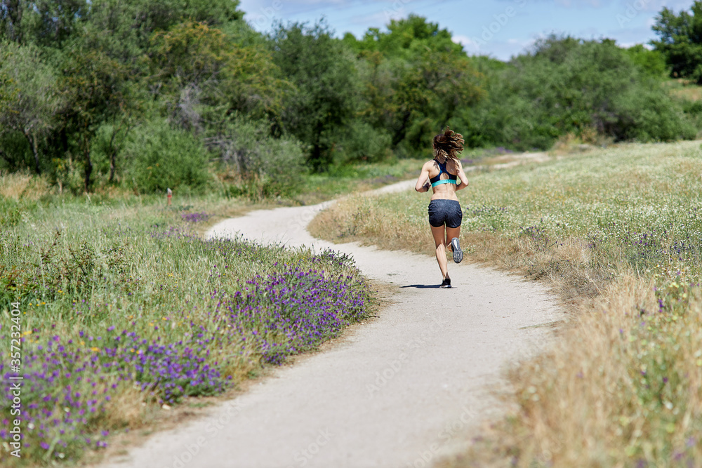 Back view of slim attractive woman running around the field. Unrecognizable person Back view of slim attractive woman running around the field. Unrecognizable person