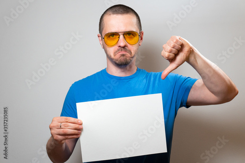 Man show thumbs down and holding blank paper