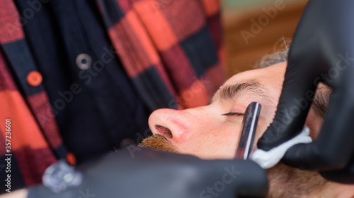 Barbershop procedures. Professional beard care. Hairdresser. Salon for men. Barber-shop. Close up portrait of bearded man with razor. Handsome bearded man with barber tools.