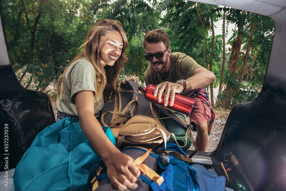 Young couple having fun while unpacking camping equipment