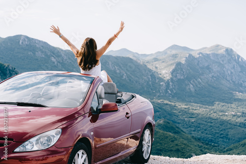 Foto Happy woman sits in a red convertible car with a beautiful view