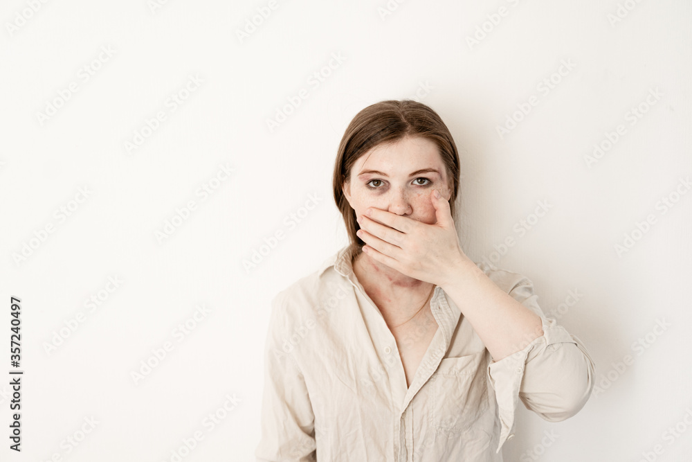girl covers her mouth with her hand, is afraid that they will tell, the victim of domestic violence on a white background girl covers her mouth with her hand, is afraid that they will tell, the victim of domestic violence on a white background