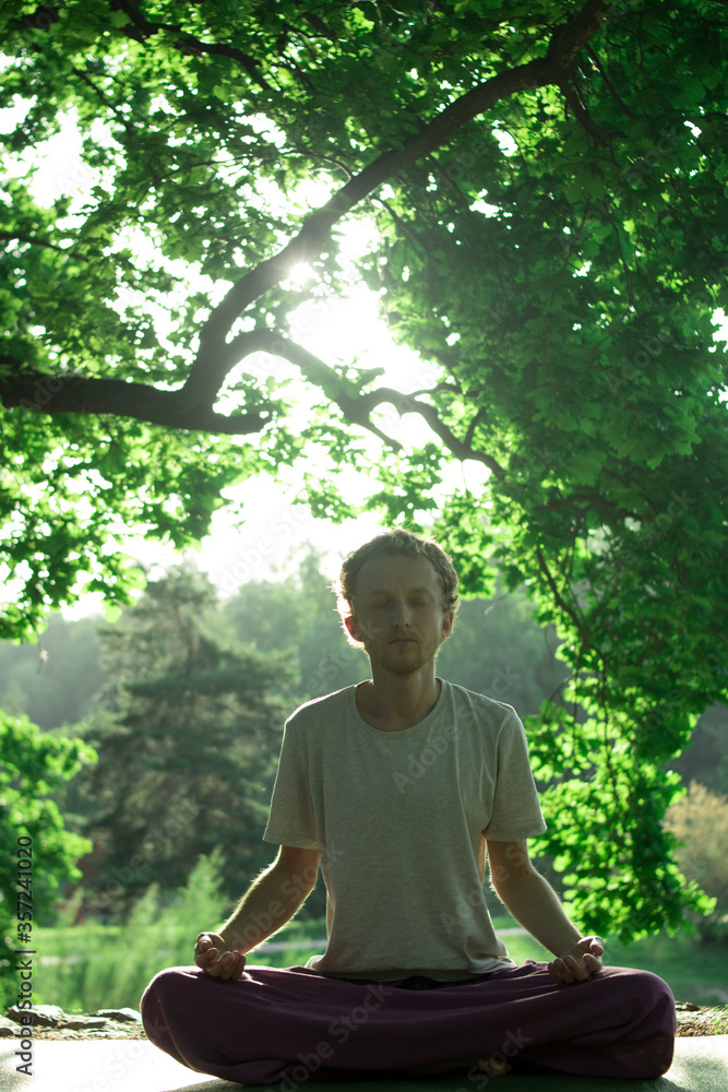Red-haired male Buddhist meditates on a background of nature Red-haired male Buddhist meditates on a background of nature