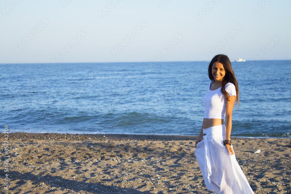 Woman dressed in white barefoot on the beach sand Woman dressed in white barefoot on the beach sand