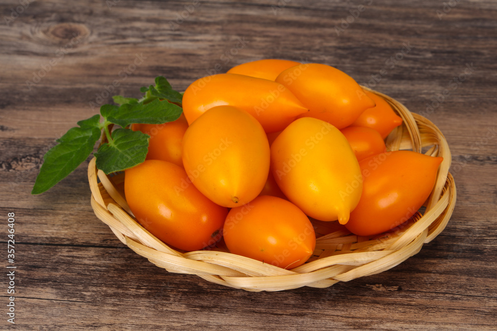 Yellow tomato heap in the wooden bowl Yellow tomato heap in the wooden bowl
