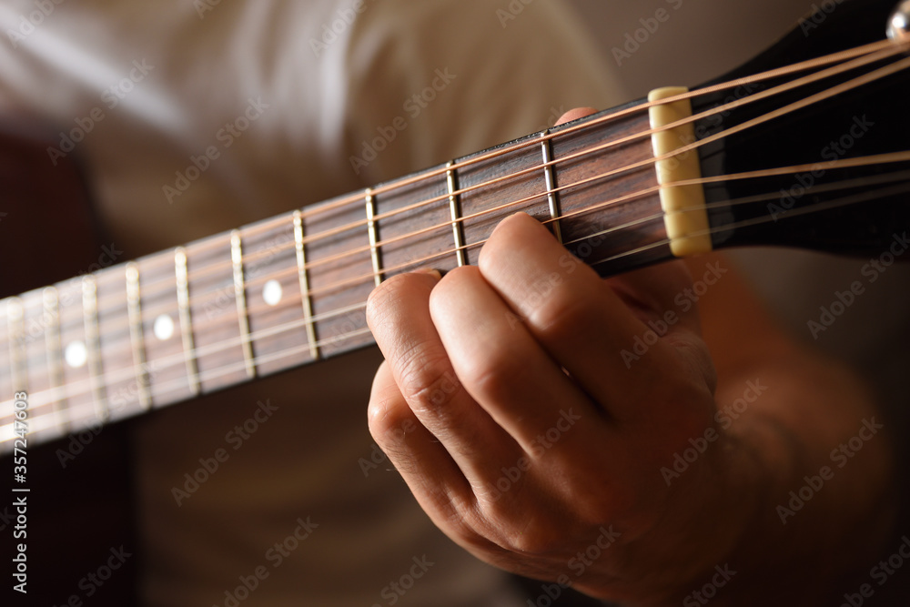 Fototapeta premium Acoustic guitar fingerboard detail and fingers doing a chord