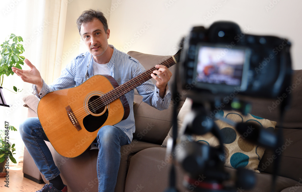Obraz premium Video Blogger doing review of a guitar recording at home