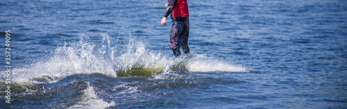 The man does wakeboarding on the water in the summer in a helmet and wetsuit.