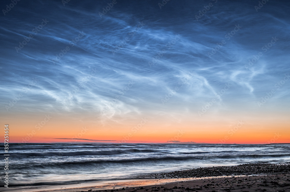 Fototapeta premium Baltic sea at night time with Noctilucent clouds. Waves in motion with clear night sky. 