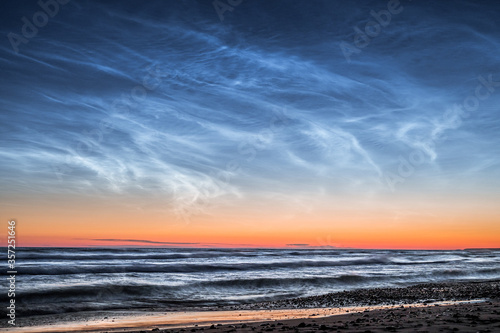 Baltic sea at night time with Noctilucent clouds. Waves in motion with clear night sky. 
 photo