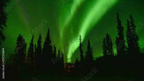 Amazing Aurora Borelis, Northern Lights seen in Yukon Territory, northern Canada in cold winter season. Green sky, lit up with movement taken with time lapse over night time.  photo