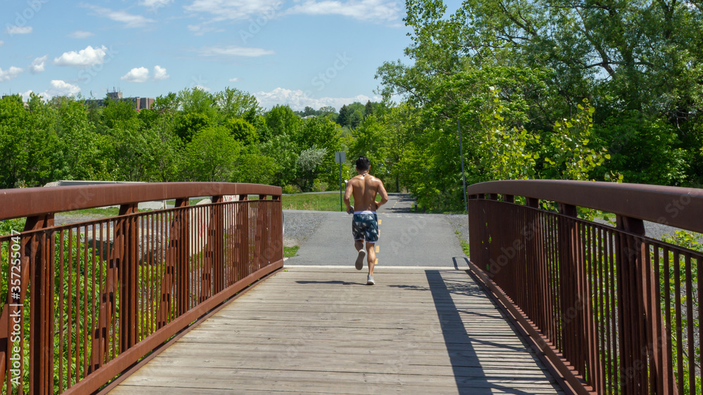 Cornwall, Ontario, Canada - 2020 June 6th man jogging without a shirt in Lamoureux Park