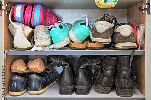 Variety of different women and men shoes packed into a wardrobe.