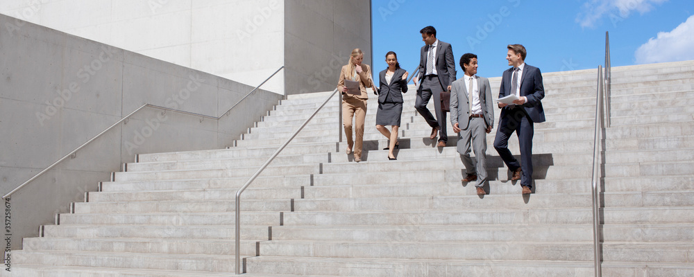 Obraz premium Business people talking and descending urban stairs