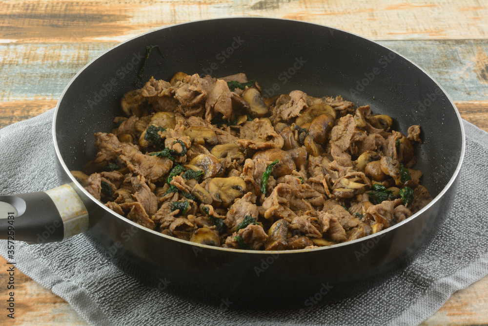 Cooking sliced beef, spinach and mushrooms for Mexican food filling in frying pan Cooking sliced beef, spinach and mushrooms for Mexican food filling in frying pan
