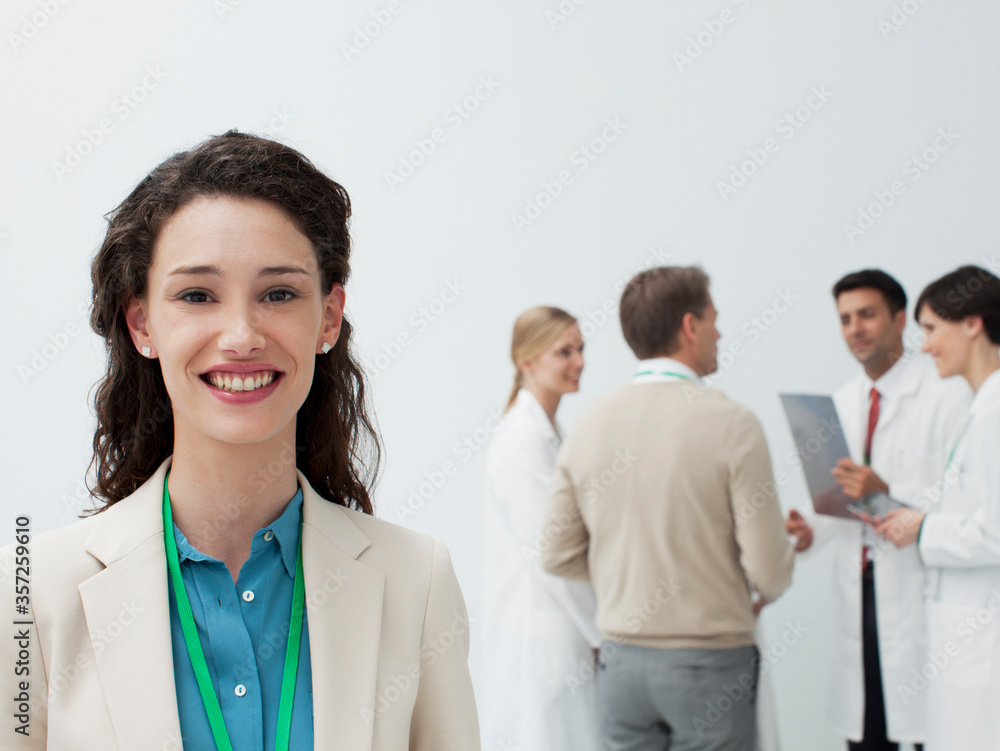 Portrait of smiling businesswoman with doctors in background Portrait of smiling businesswoman with doctors in background
