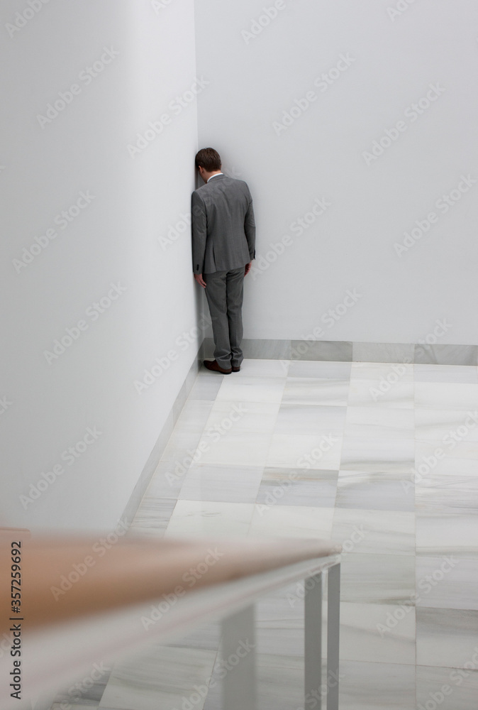 Dejected businessman standing in corner Dejected businessman standing in corner