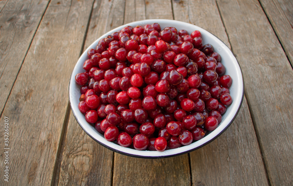A bowl of sweet cherries on a wooden background A bowl of sweet cherries on a wooden background