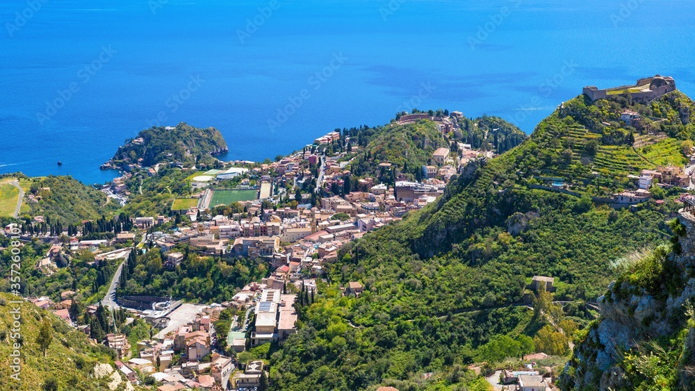 Aerial view of Taormina, on right is Castello Saraceno, in center is Ancient Greek theatre. Taormina located on Sicily island in Italy.
