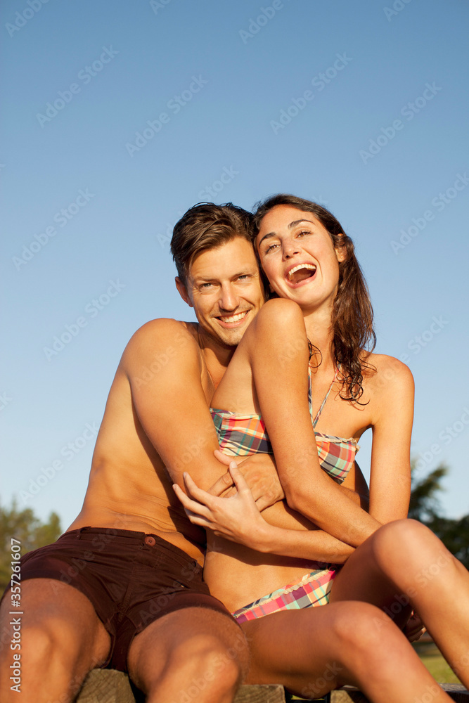 Portrait of smiling man hugging enthusiastic woman in bikini