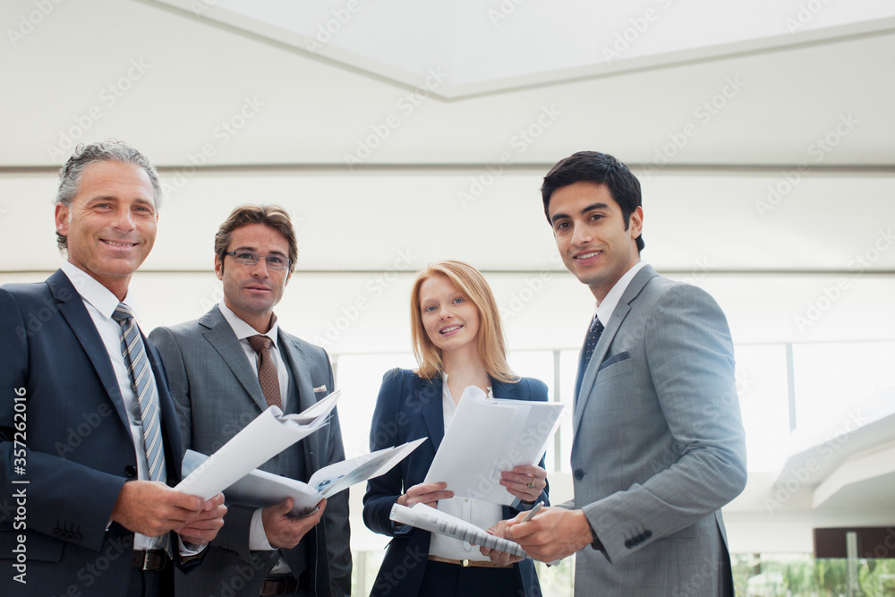 Portrait of smiling business people reviewing paperwork Portrait of smiling business people reviewing paperwork