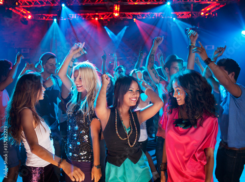 Photo Smiling friends dancing on dance floor of nightclub